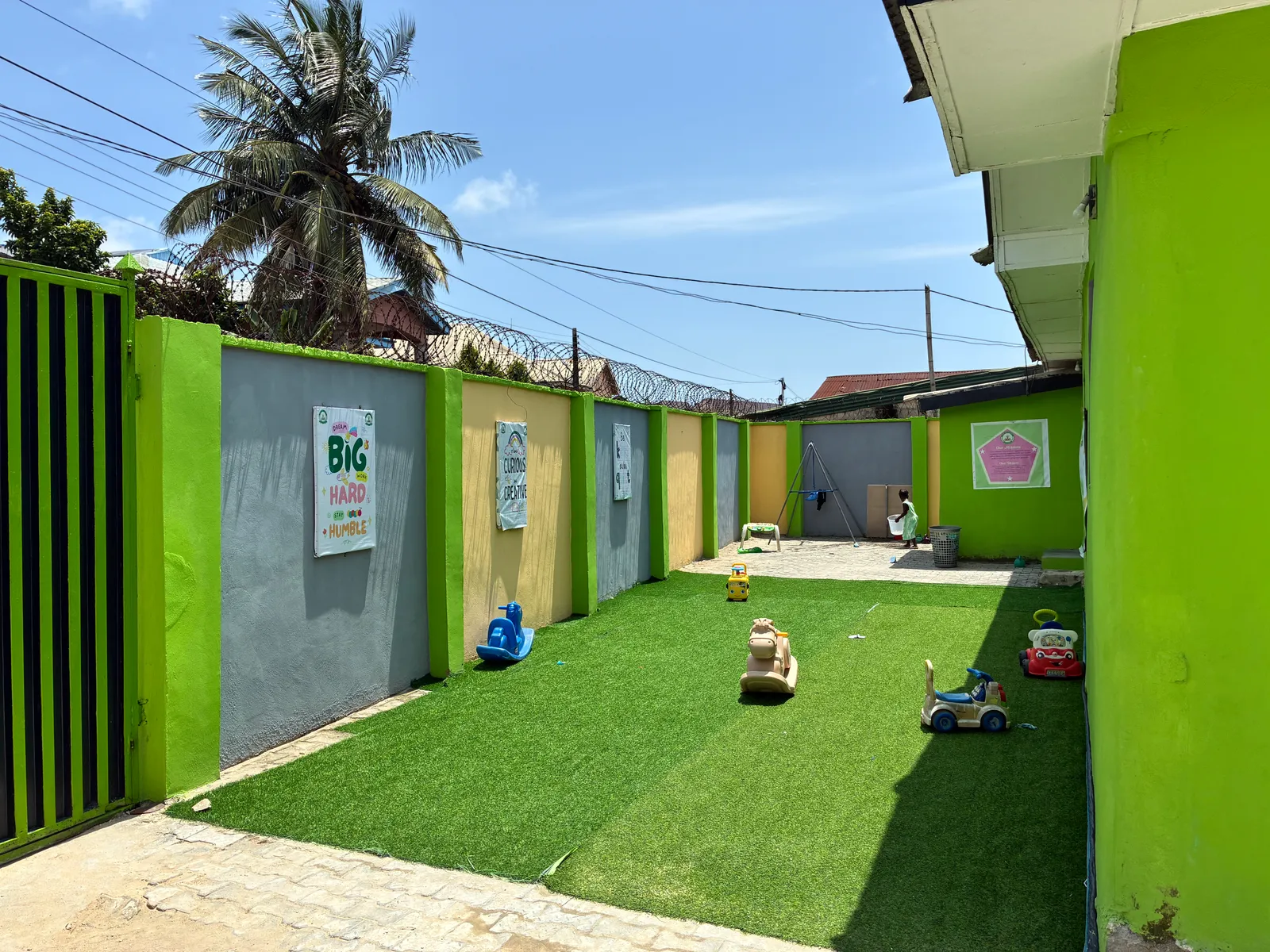 The outdoor play area with ride-on toys and a swing